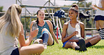 Women, talk and team on grass for hockey, break or water bottle for hydration, smile and relax on field. People. group and happy with conversation, fitness and training on ground at sports club