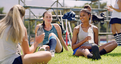 Buy stock photo Women, talk and team on grass for hockey, break or water bottle for hydration, smile and relax on field. People, group and happy with conversation, fitness and training on ground at sports club
