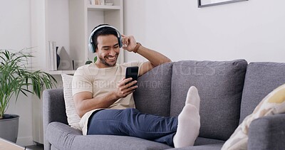Buy stock photo Relax, phone and music with man on sofa for streaming, radio station and audio playlist. Podcast subscription, headphones and media platform with person in living room of home for connection