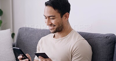 Buy stock photo Credit card, phone and smile with man on sofa for online shopping, banking app and password. Digital purchase, coupon code and ecommerce with person in living room of home for bills and fintech