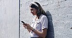 Reading, smile and woman on wall with phone, post reaction or chat update on weekend break. Happy, digital and girl on plaster background with mobile, scroll or online messaging on Sunday afternoon.