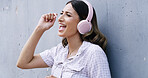 Happy woman, singing and listening to music with headphones for vibe on a wall background. Excited, female person or model with smile, earphones or app for audio streaming, sound karaoke or podcast