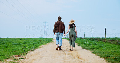 Buy stock photo Couple, back view and holding hands on farm for adventure, journey or walk in countryside. Man, woman or farmland with blue sky, grass field or dirt road for natural sustainability or eco production