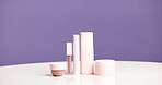 Makeup, bottles and product range in studio for beauty aesthetic, skincare routine and marketing. Space, cosmetic selection or container for dermatology, wellness or advertising on purple background.