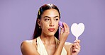 Makeup, mirror and sponge with woman in studio for cosmetics, contour and beauty maintenance. Self care, glow and blush with person on purple background for highlighter shine, foundation and gen z