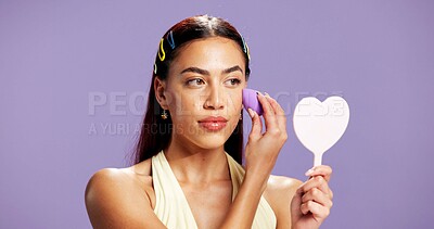 Buy stock photo Makeup, mirror and sponge with woman in studio for cosmetics, contour and beauty maintenance. Self care, glow and blush with person on purple background for highlighter shine, foundation and gen z