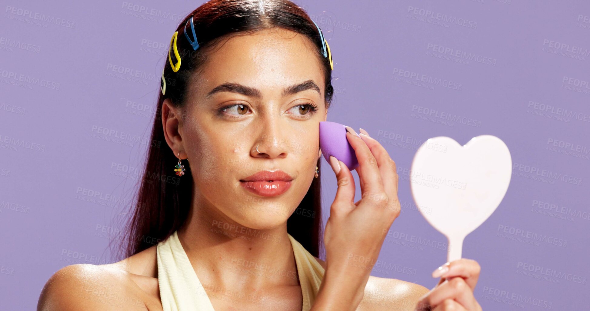 Buy stock photo Beauty, mirror and sponge with woman in studio for cosmetics, contour and makeup maintenance. Self care, glow and blush with person on purple background for highlighter shine, foundation and gen z