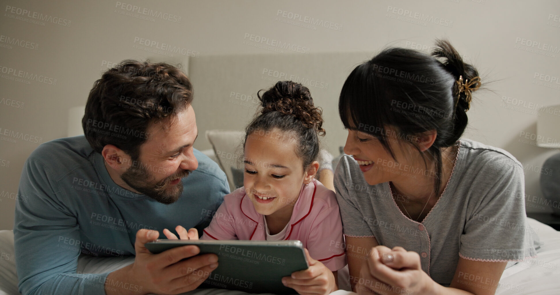 Buy stock photo Parents, girl and tablet in bed, smile and bonding with online games, scroll or problem solving in home. People, mother and daughter with dad, tech and relax with app for puzzle at family house