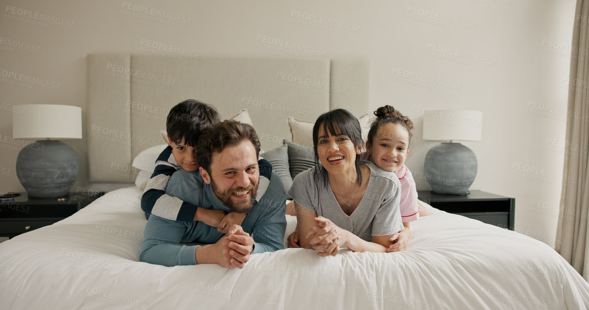 Buy stock photo Parents, children and portrait on bed with play, smile and bonding for love with pyjamas at house. People, mom and dad with kids, happy or relax in morning, care and laugh at family home in Spain