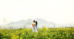 Love, couple and kiss on field for connection, care and holding hands with space on holiday. Romance, man and woman in countryside with flowers on vacation, commitment and bonding together outdoor