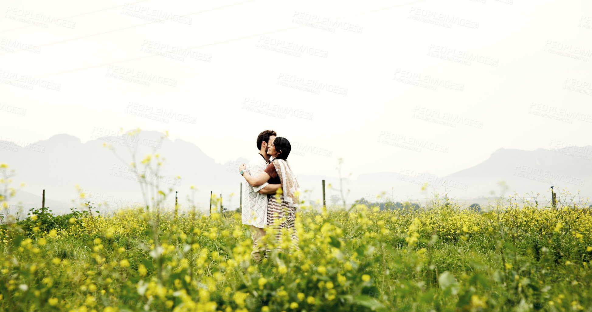 Buy stock photo Love, couple and hug on field on holiday, care or romance for connection with mockup space. Embrace, man and happy woman in countryside with flowers on vacation, loyalty or bonding together outdoor