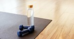 Yoga, water and equipment with dumbbells in studio for fitness, empty room and wellness class. Pilates session, electrolyte bottle and interior of health club for training weights, holistic and gym