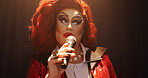 Person, drag artist and singing at concert, stage and spotlight with pride, music and event. Lgbt performer, creative and voice with celebration, song and makeup with microphone at cabaret show