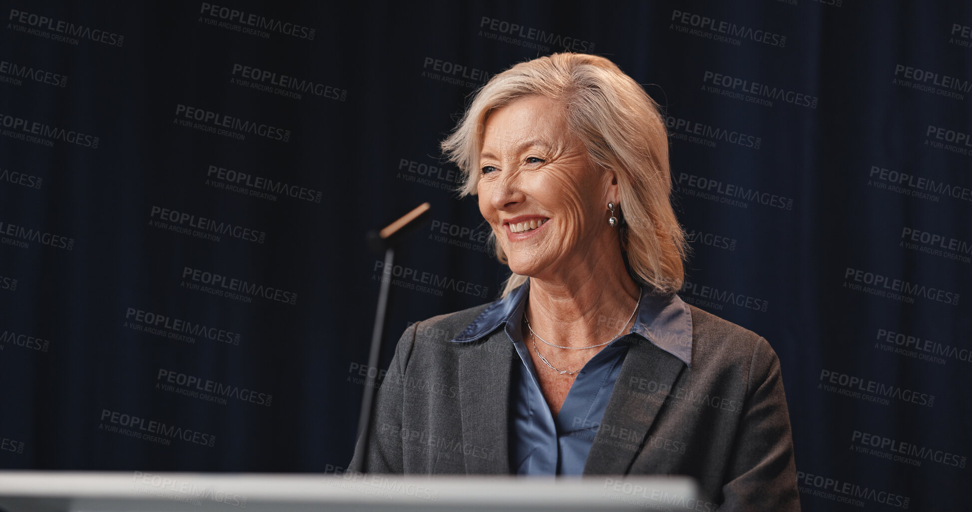 Buy stock photo Politics, smile and speech with mature woman on stage for democracy, election or government campaign. Happy, microphone and podium with speaker at conference, meeting or summit for support or vote