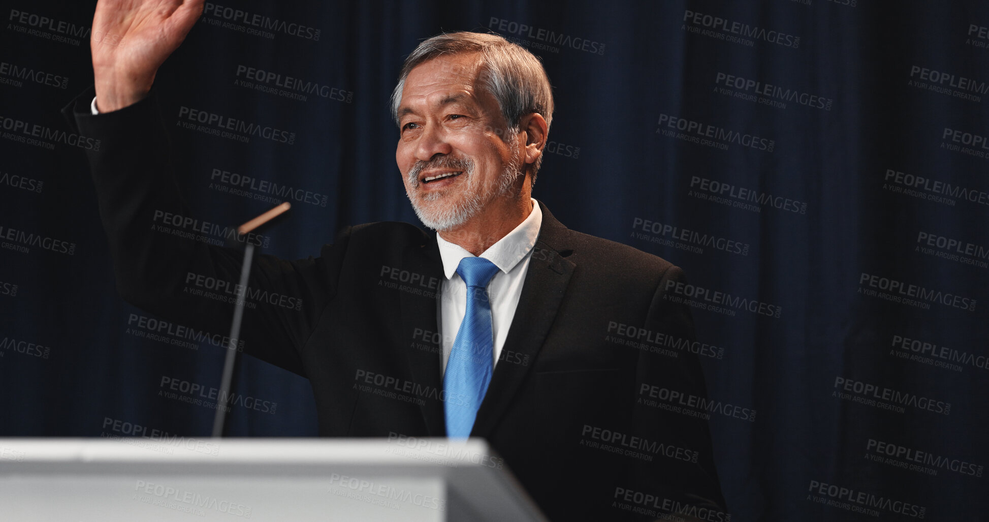 Buy stock photo Wave, Asian man and politician on stage for election, democracy or political campaign. Speech, greeting and mature speaker at conference, meeting or seminar event for vote or activism at convention