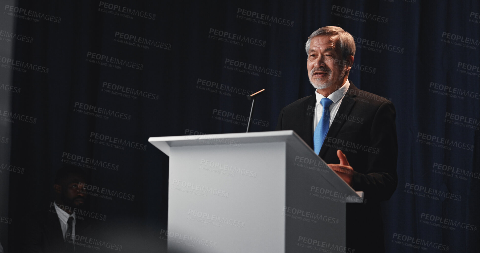 Buy stock photo Podium, mature man and politician with mic for election, democracy or political campaign. Speech, greeting and guest speaker at conference, meeting or seminar event for vote or activism at convention