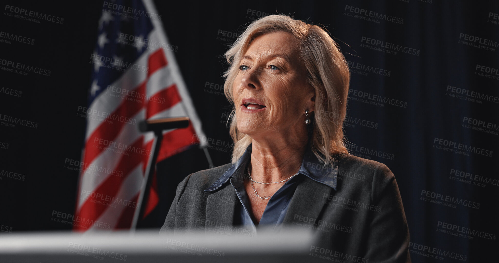 Buy stock photo Politician, speaker and woman with American flag by podium for election, debate or voting campaign. Government, candidate and mature person on stage for press conference, political policy and speech