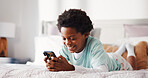 Relax, smile and kid with phone in bedroom for game, social media and internet communication in home. African boy, bed and app for streaming service, cartoon and watch video on weekend online