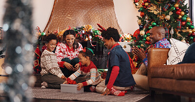 Buy stock photo Christmas, parents and children in home with gift for festive holiday, tradition and bonding together. Happy family, kids and open present in living room for xmas decoration, support and celebration.
