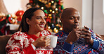 Coffee, christmas and couple on sofa in house with bonding, connection or marriage in living room. Happy, love and man with woman for drinking eggnog for festive weekend with xmas tradition in home.