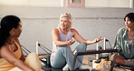 Pilates, talking and women in machine in gym for fitness advice, workout tips and exercise. Health club, trainer and friends in discussion, chat or conversation on reformer for wellness in studio