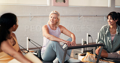 Buy stock photo Pilates, conversation and happy women in studio for fitness advice, workout tips and exercise. Health club, instructor and friends in discussion, chat and talking on reformer machine for wellness