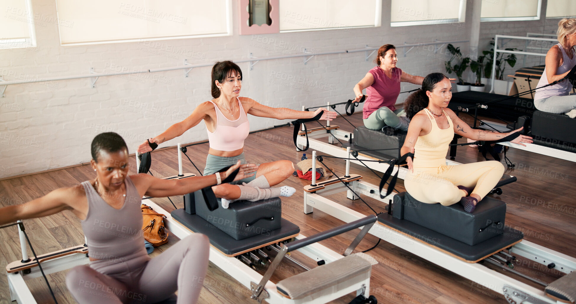 Buy stock photo Women, stretching and pilates class with reformer for flexibility, exercise or training in gym. Active, female people or group with fitness equipment or machine for workout or balance in health club