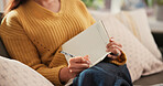 Woman, hands and writing on sofa with journal for planning goals, creative idea or process emotions. Daily reflection, notes or person in home with diary for self improvement, inspiration or insight.