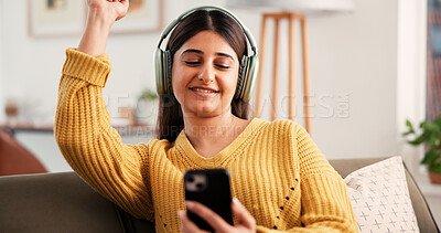 Buy stock photo Woman, phone and dance on sofa with headphones, happy and listen to music in living room at home. Person, smartphone and smile with audio, streaming subscription and mobile app on couch at apartment