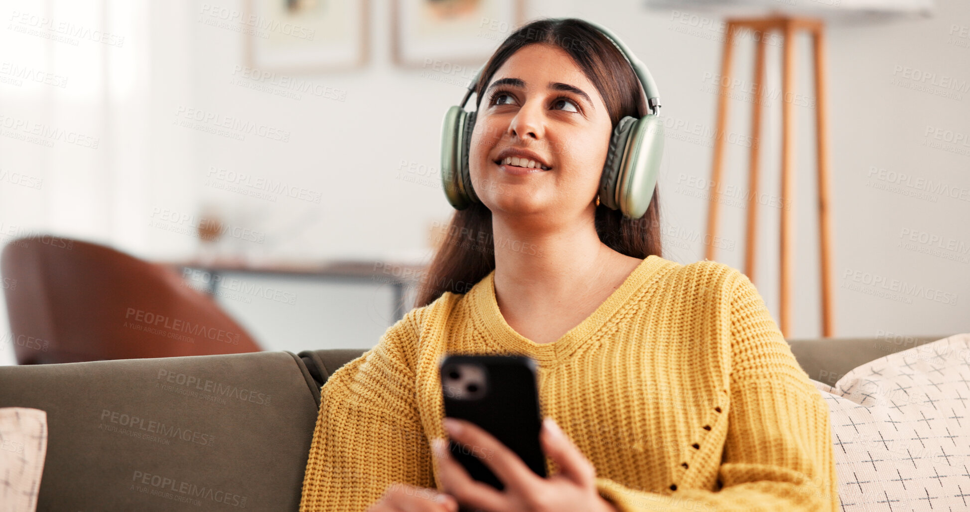 Buy stock photo Thinking, headphones and woman with phone in home, streaming podcast or listening to music. Smile, mobile and person with idea for audio on sofa in living room, online radio and playlist decision