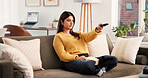 Watching tv, online and woman with remote, home and streaming movie with subscription in living room. Channel, change and Indian person with controller for entertainment, chill or comfortable on sofa
