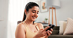 Woman, phone and fitness with typing in home for online tips, workout app and social media. Internet tutorial, digital exercise guide and smile with person in living room of house for wellness