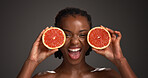 Skincare, grapefruit and portrait of black woman in studio with natural, health or organic glow. Vitamin c, smile and African person with citrus fruit for dermatology hydration by gray background.