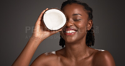 Buy stock photo Beauty, coconut and black woman in studio with natural, health and organic facial glow. Happy, skincare and African female person with fruit for face hydration with dermatology on gray background.