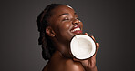 Skincare, coconut and black woman in studio with health, natural and organic facial glow. Happy, space and African female person with fruit for face hydration with dermatology by gray background.