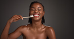 Black woman, brushing teeth and happy in studio portrait, hygiene and mockup space on dark background. African person, bamboo toothbrush or smile with sustainable product for oral wellness in Nigeria