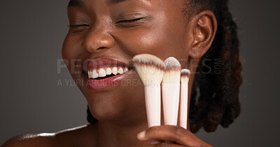 Buy stock photo Brush, makeup and happy black woman in studio for cosmetics, makeover and application. Cosmetology, smile and person with tools for foundation, beauty products and salon aesthetic on dark background