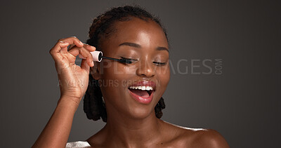 Buy stock photo Mascara, application and black woman in studio for cosmetics, volume and length boost in eye prep. Beauty, smile and female person on gray background with tool, natural or lash lift with makeup