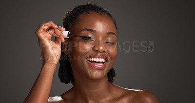 Buy stock photo Cosmetics, application and black woman in studio with mascara, volume and length boost in eye prep. Beauty, smile or female person on gray background with tool, natural or lash lift in makeup results