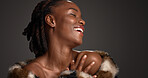 Black woman, laugh and makeup for beauty in studio with cosmetics, facial glow and aesthetic. Space, female person and confidence of luxury shine, fur coat and glamour for makeover on gray background