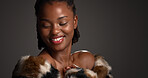 Smile, black woman and confident for beauty in studio with cosmetics, facial glow and aesthetic. Space, female person and makeup for luxury shine, fur coat and glamour for makeover on gray background