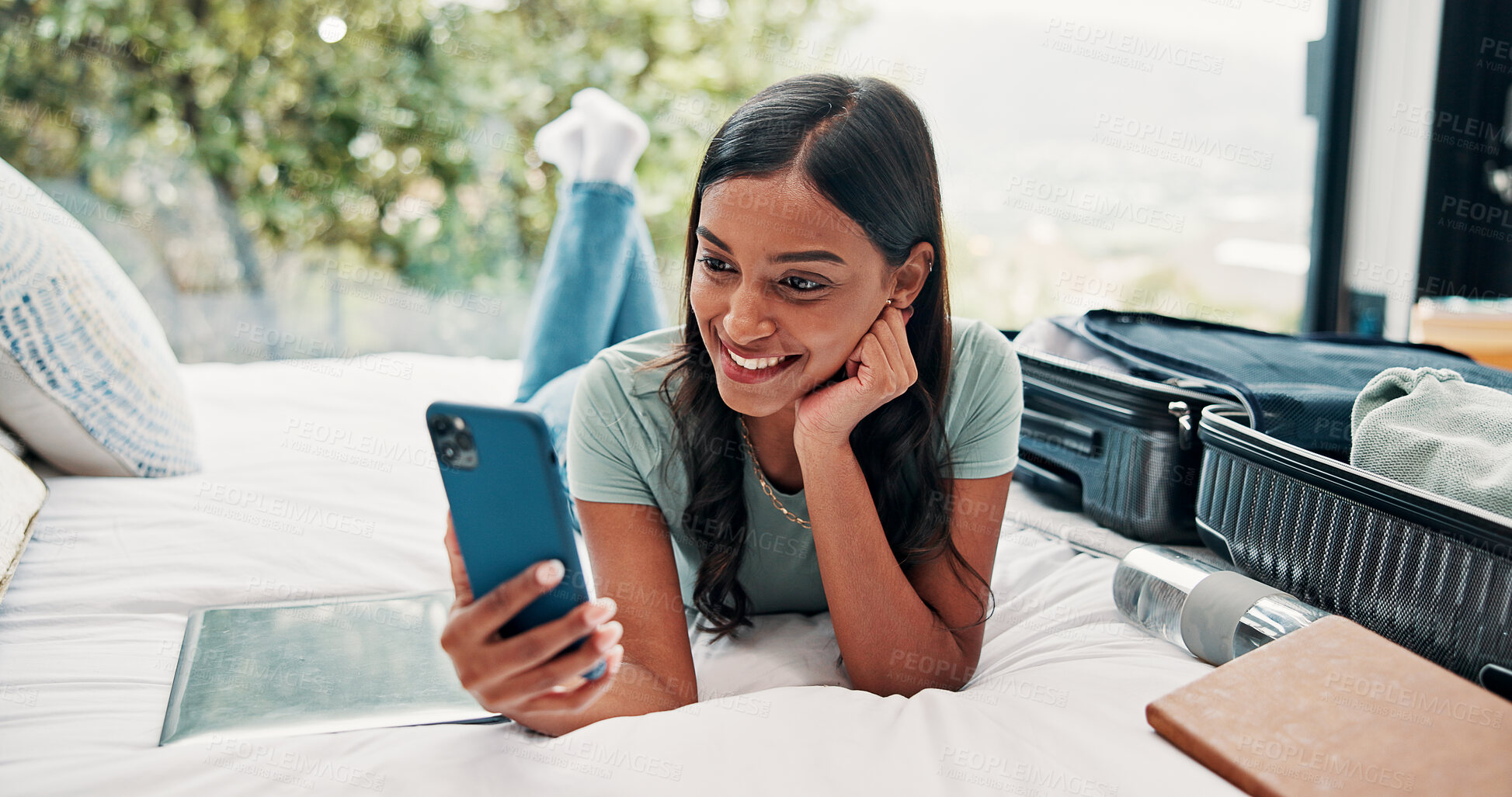 Buy stock photo Phone, video call and happy woman with luggage on bed, travel vacation or connection for online chat. Holiday lodge, hotel room and indian person with suitcase for trip, conversation or mobile app