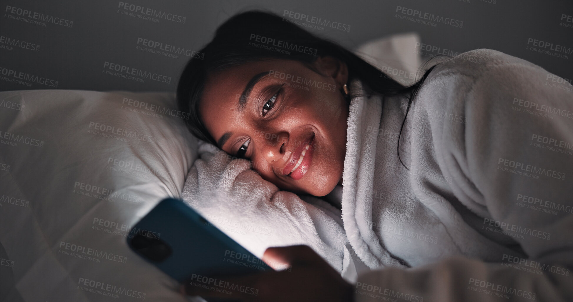 Buy stock photo Streaming, night or woman in bedroom with phone, online reading or video browse on social media. Smile, dark or girl in house with tech, e book subscription or digital scroll in late evening.