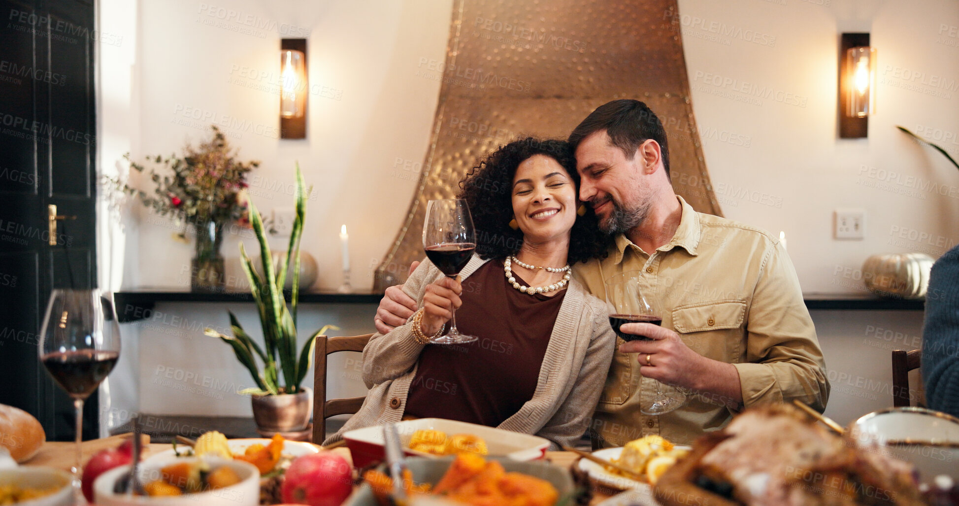 Buy stock photo Thanksgiving, wine and hug with couple in dining room for holiday season, dinner or tradition. Festive feast, party and drink with man and woman in family home for food, hosting and hospitality