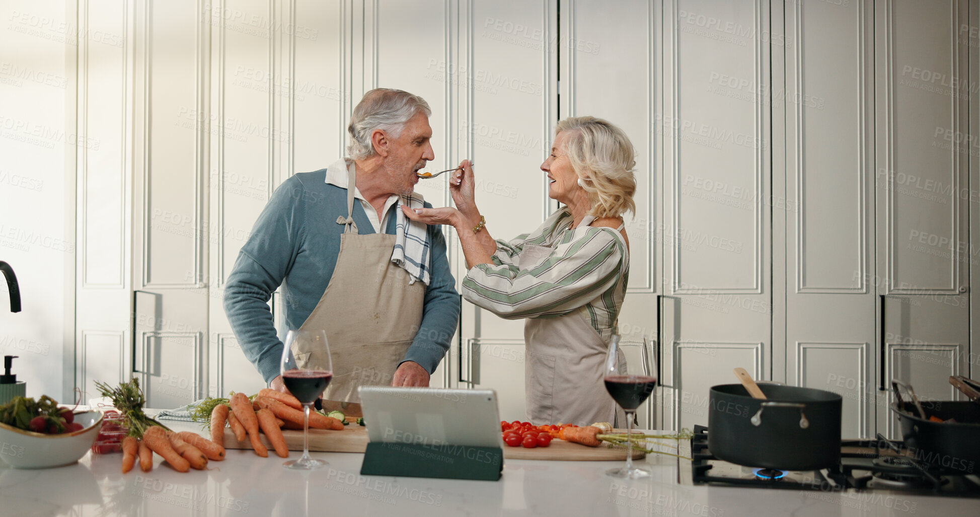 Buy stock photo Cooking, taste and senior couple in kitchen for lunch, online recipe and prepare food for bonding in home. Tablet, retirement and old man and woman for meal prep, wine and help for anniversary dinner