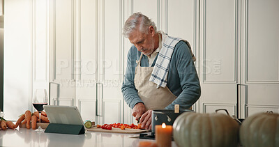 Buy stock photo Mature man, tablet or cutting on kitchen counter, ingredient preparation or video tutorial for dinner. Online recipe, blog post or person chop vegetables for healthy food, tech or cooking instruction