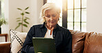 Senior woman, tablet and reading in living room with online news, blog post and sofa. Relax, digital tech and mature person with app, internet scroll or social media in home for retirement with flare