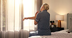 Back, stretching and woman in bedroom, morning and wellness with lens flare, relax and calm. Home, pensioner and mature person on bed, flexibility and start day with peace, wake up and muscle relief