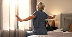 Back, stretching and woman in bedroom, wake up and wellness with lens flare, routine and calm. Home, pensioner and mature person on bed, circulation and start day with peace, morning or muscle relief
