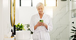 Mature woman, phone and typing in bathroom to search morning news, texting and scroll social media. Robe, house and person with smartphone for online research, communication and check notifications